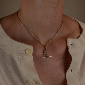 Gold necklace with a pendant worn by a person against a neutral background