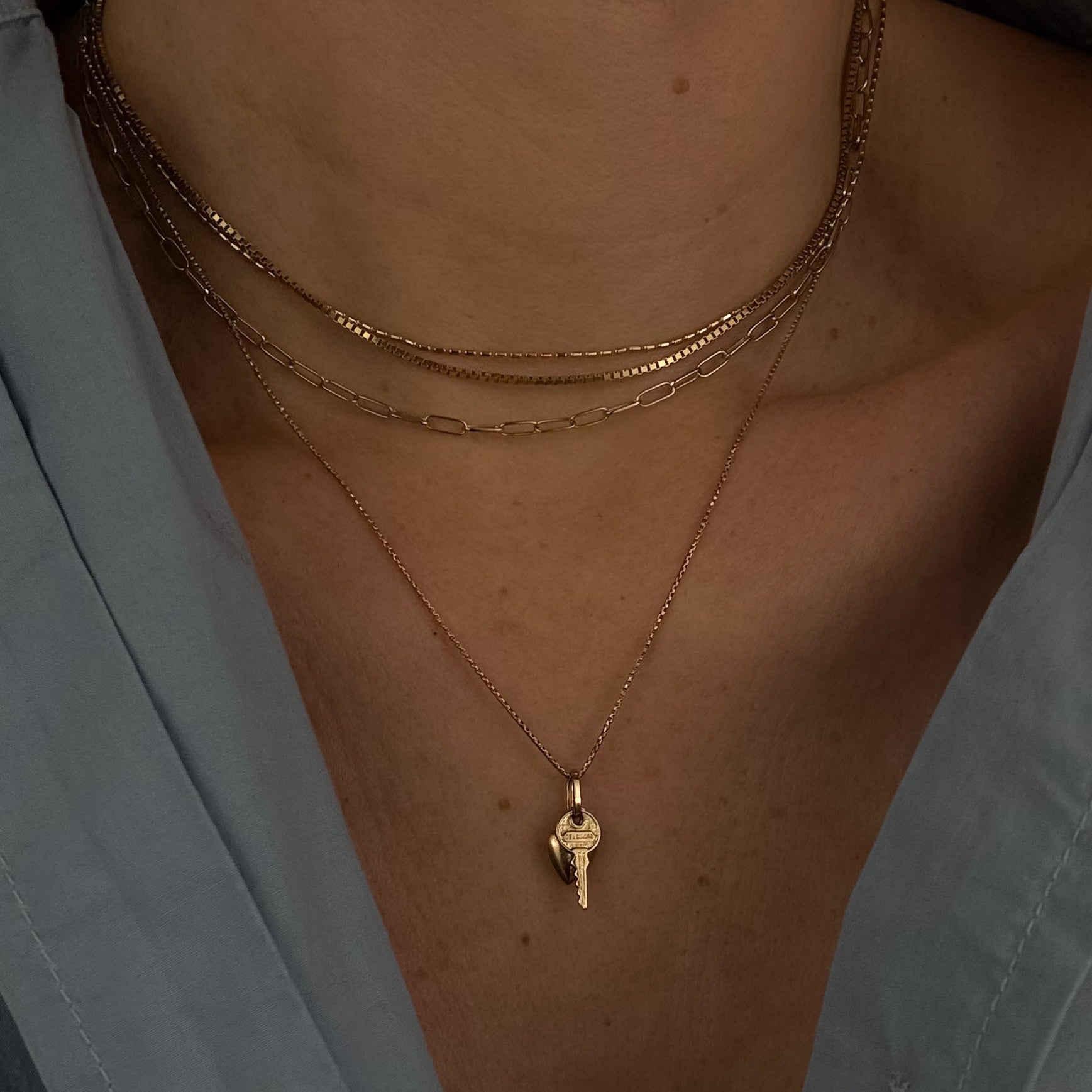 Close-up of a person wearing a gold necklace with a small pendant.
