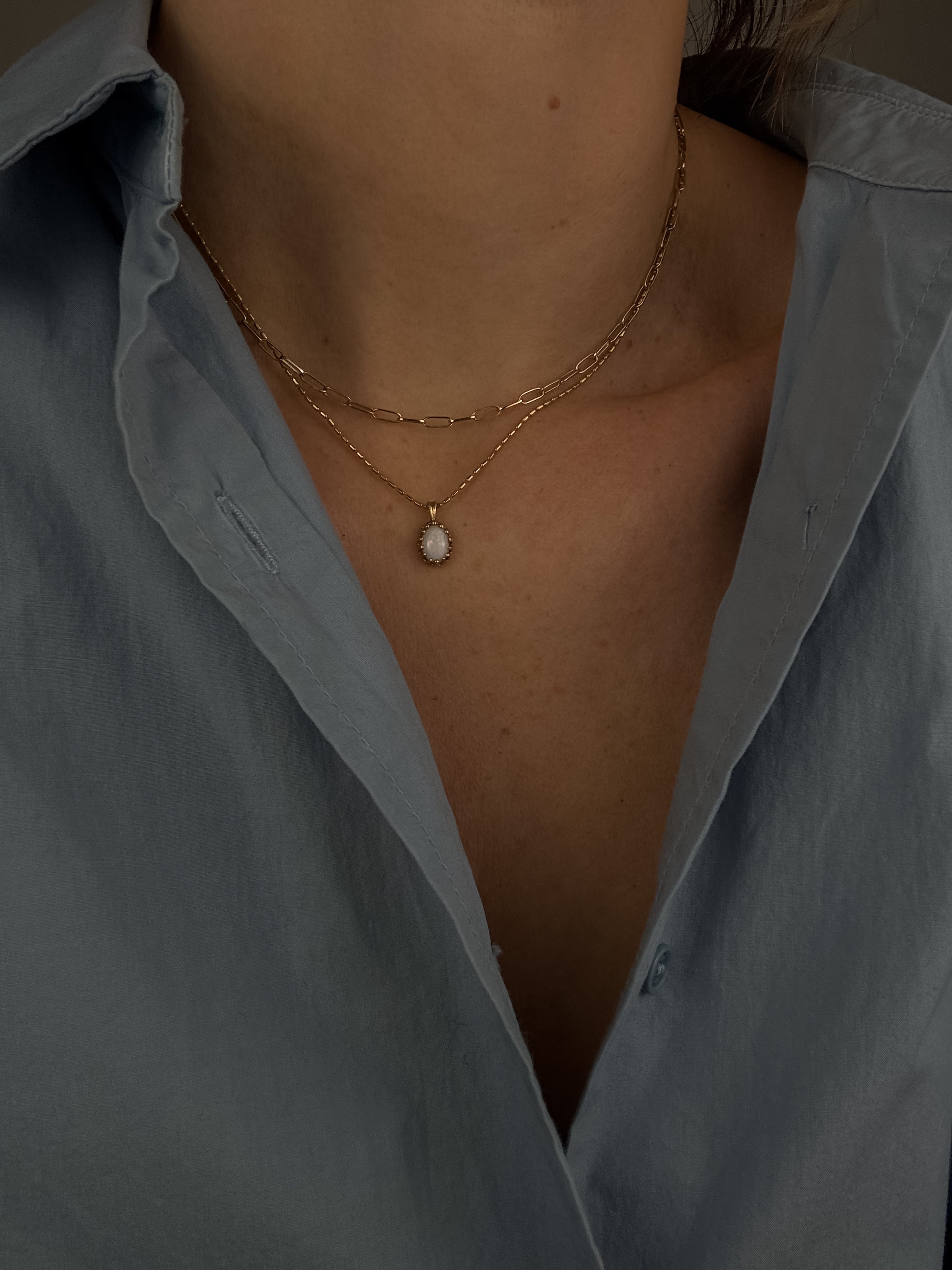 Necklace with a pendant worn by a person wearing a light blue shirt.