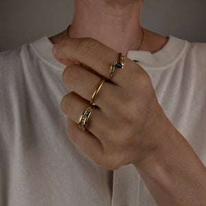 Close-up of a person wearing gold rings on a neutral background