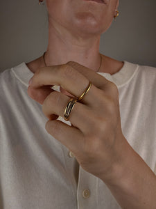 Close-up of a person wearing gold rings on a neutral background