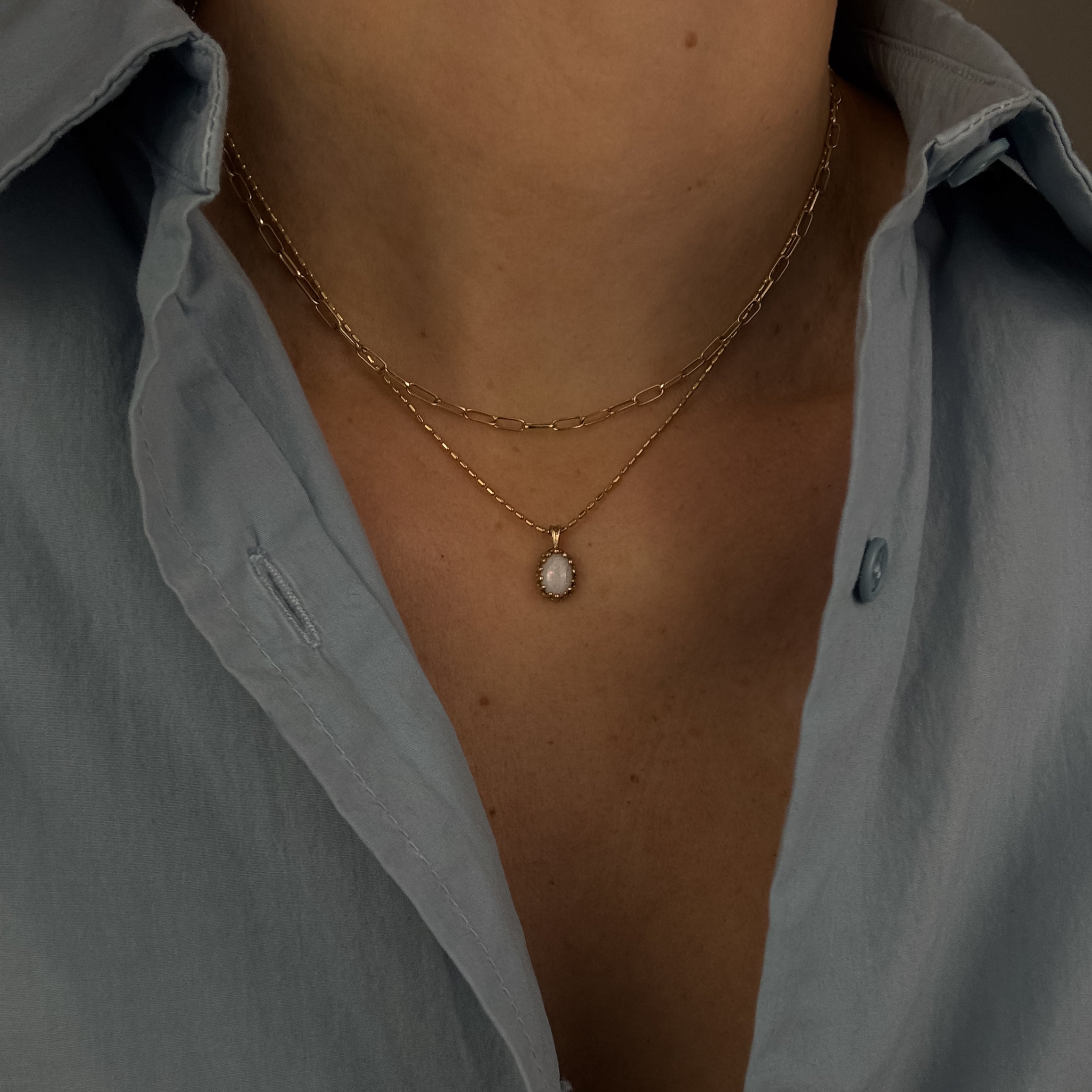 Necklace with a pendant worn by a person wearing a light gray shirt.