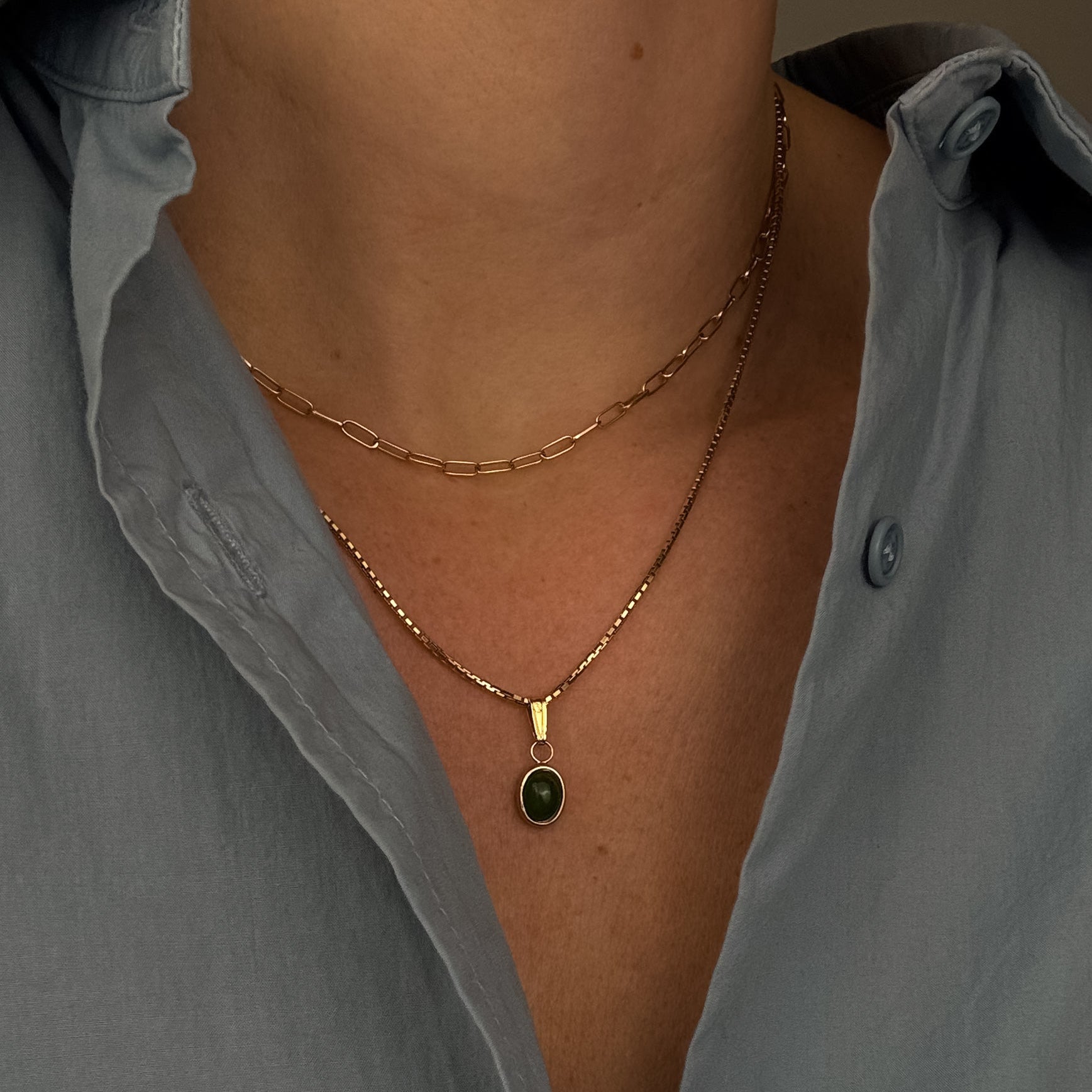 Necklace with a pendant worn by a person wearing a light gray shirt.