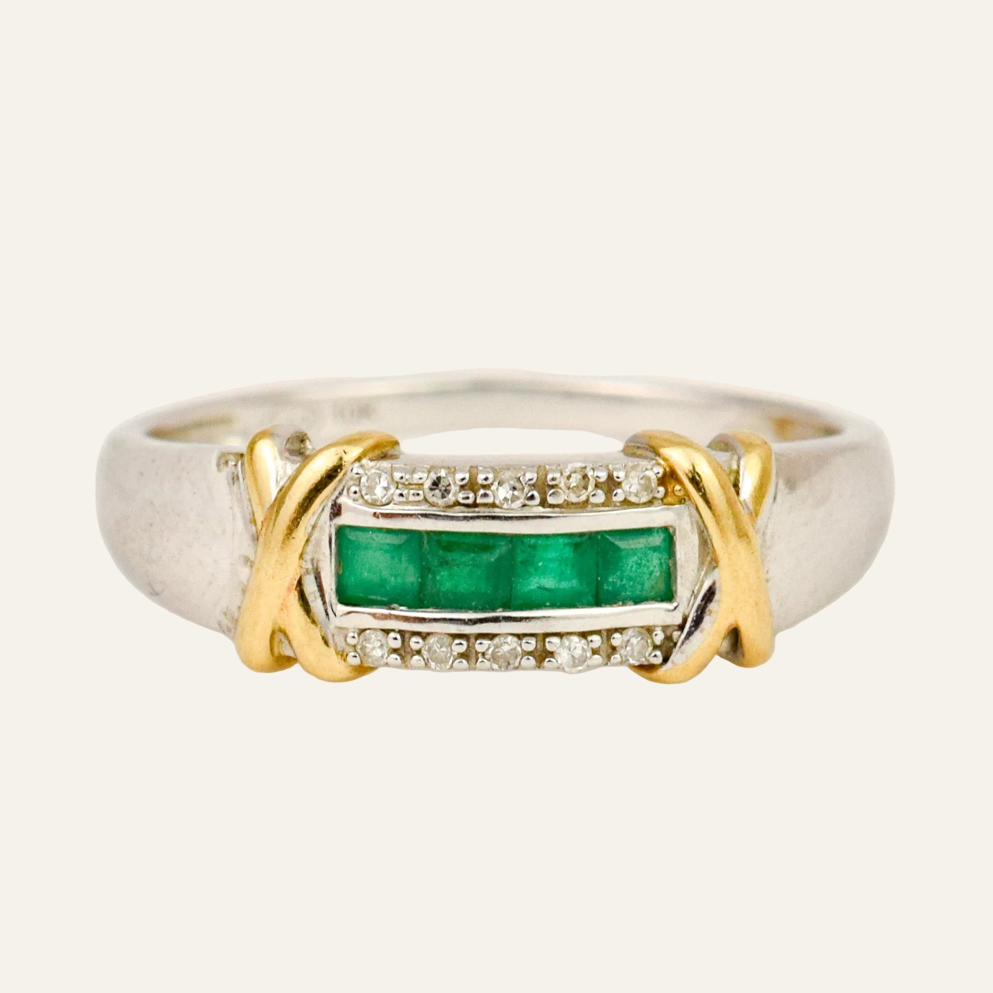 Two-tone 10k gold ring with a row of square-cut green emeralds framed by round diamonds, yellow gold X on each white gold shoulder
