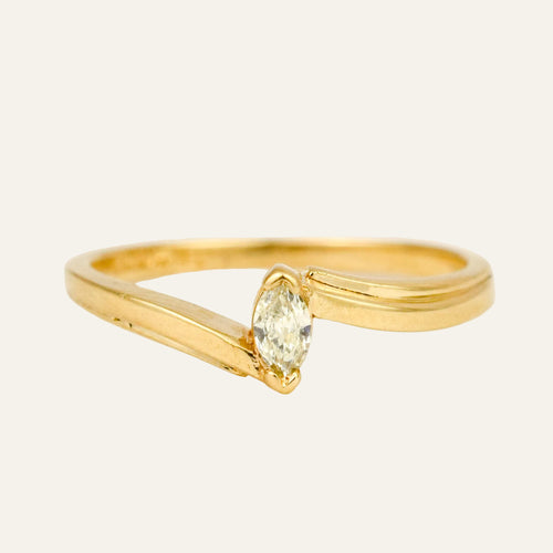 Slim 10k yellow gold bypass ring with a single marquise diamond set on the diagonal where the band crosses