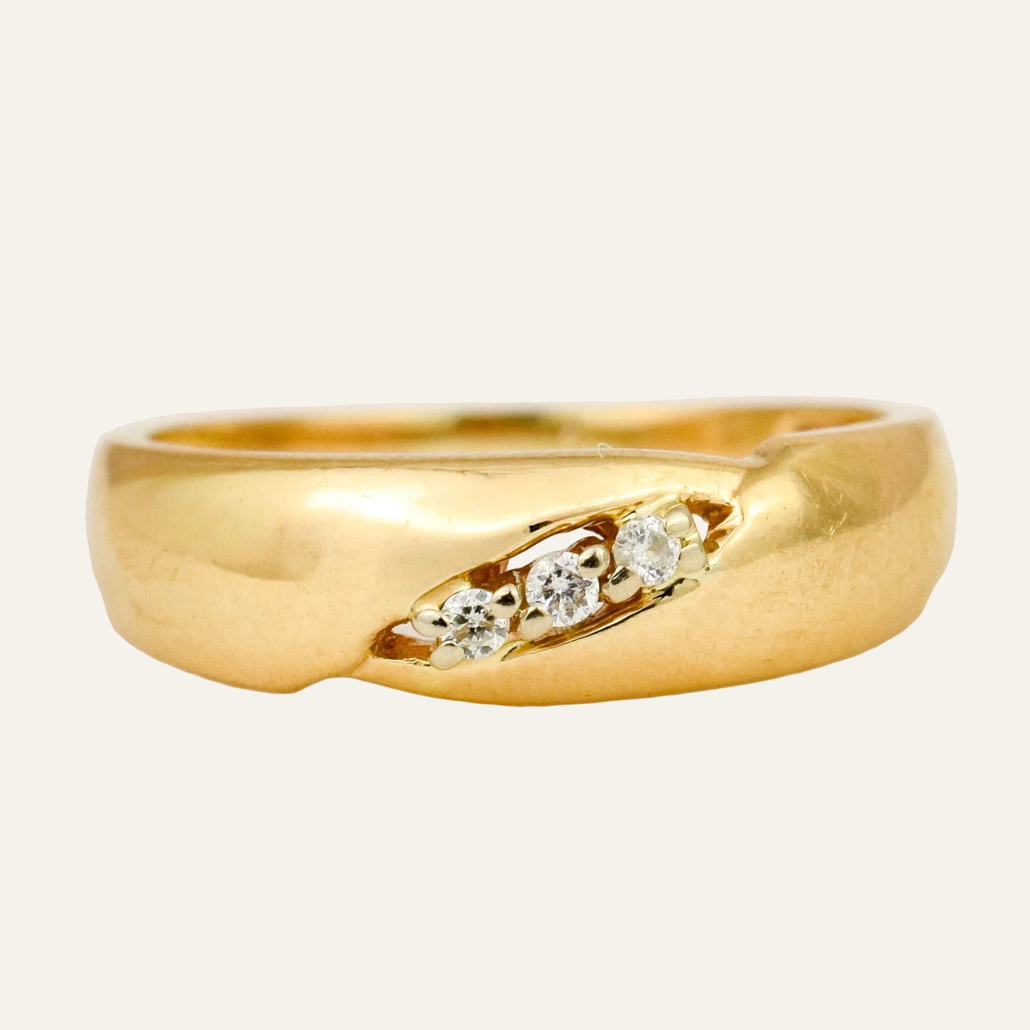 Domed 14k yellow gold band set with three small round diamonds running on the diagonal across the top