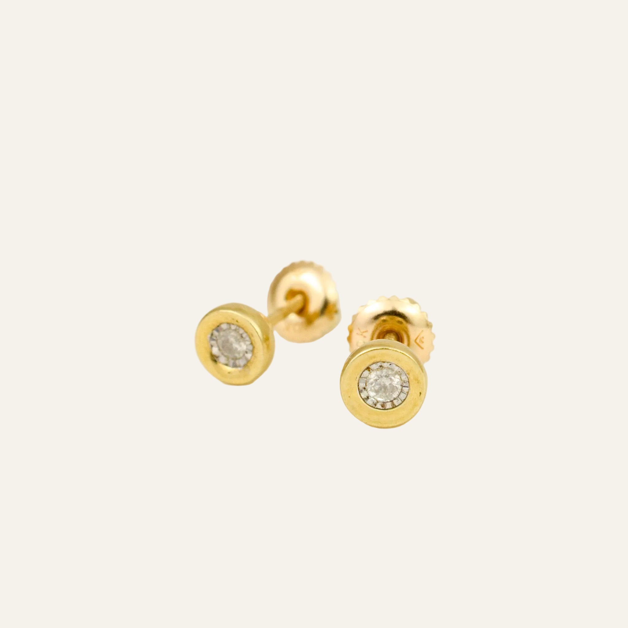 Pair of bezel-set round diamond stud earrings in 10k yellow gold with screw-back posts