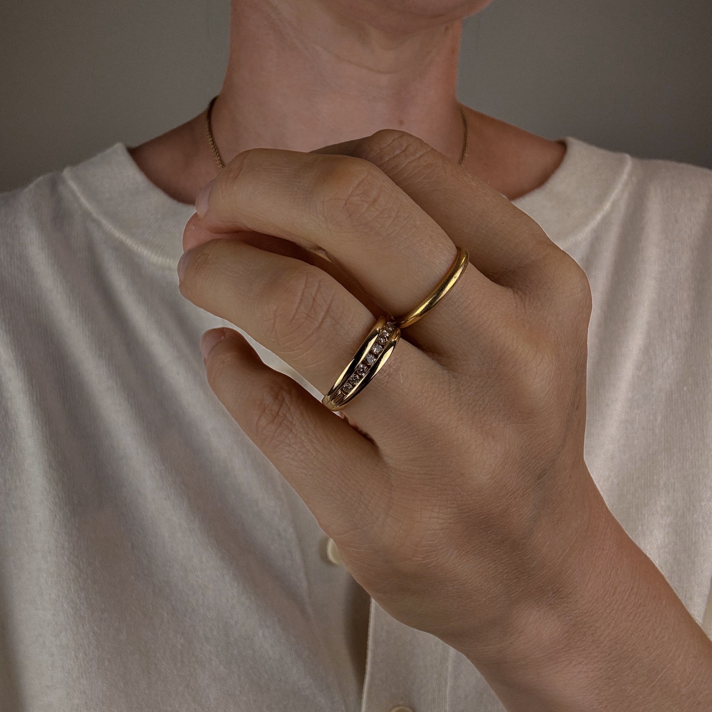 Close-up of a person wearing a gold ring on a neutral background