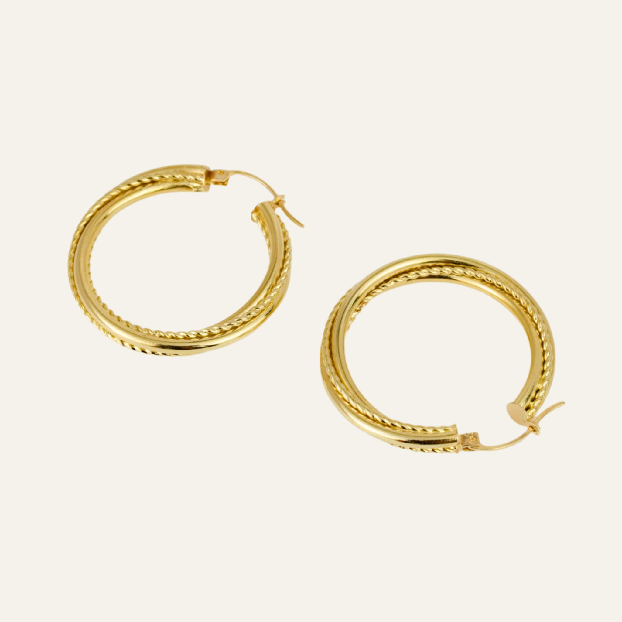 Gold hoop earrings on a light beige background