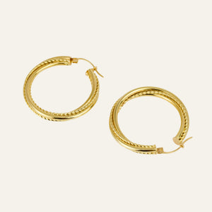 Gold hoop earrings on a light beige background
