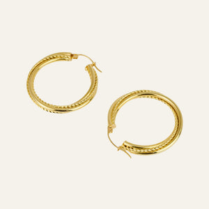 Gold hoop earrings on a light beige background