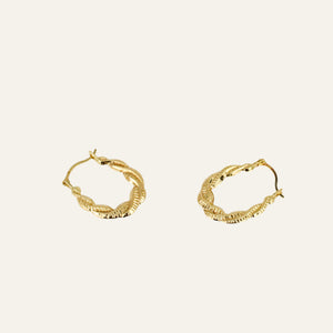 Gold hoop earrings on a light gray background