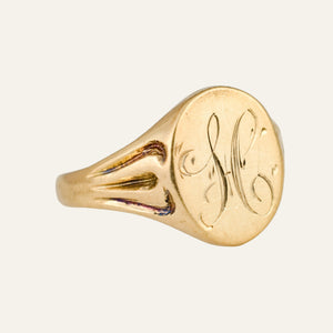 Gold ring with engraved initials on a light gray background