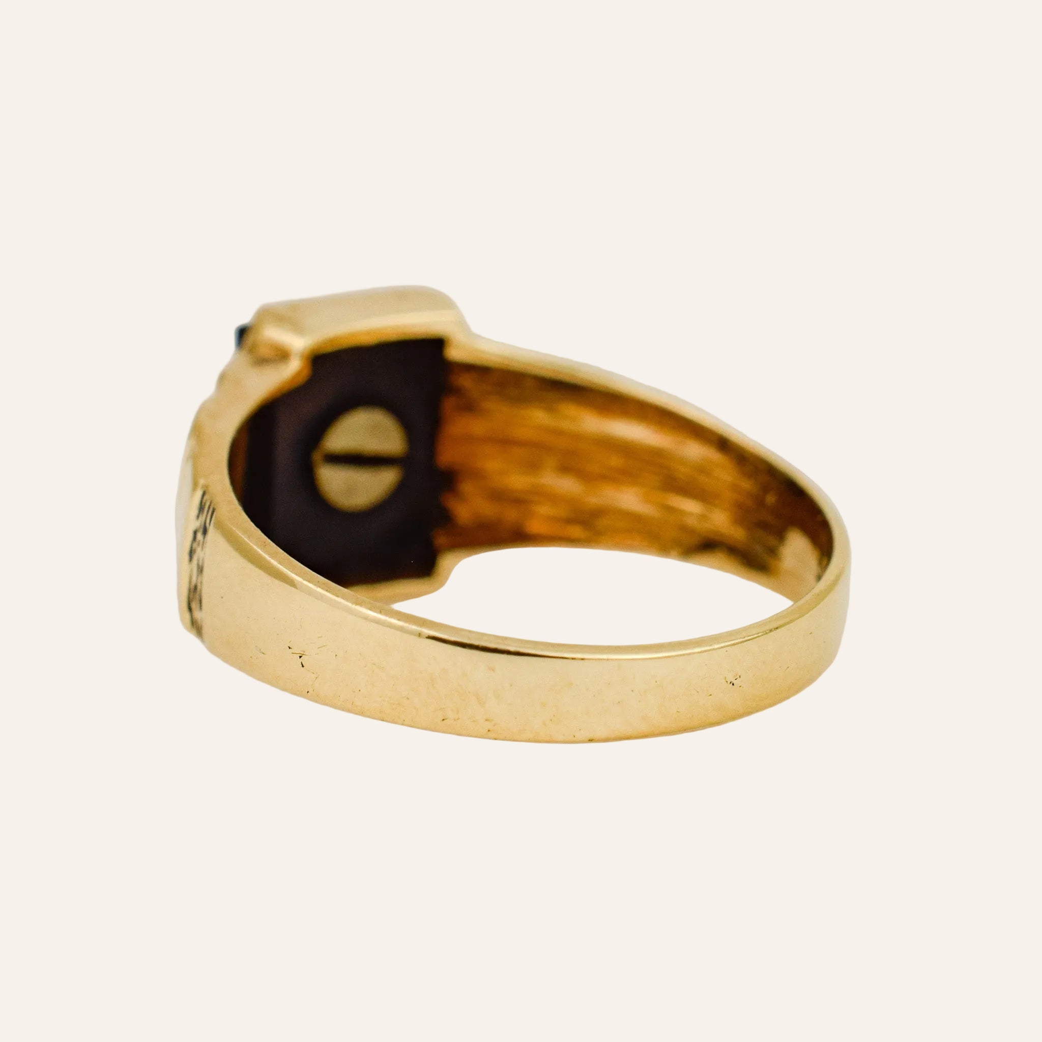 Gold ring with a black stone on a light gray background