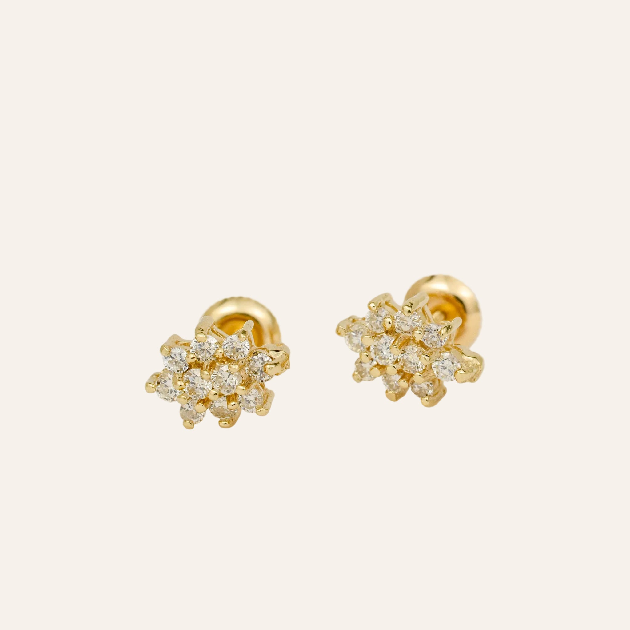 Pair of gold earrings with diamond-like stones on a white background