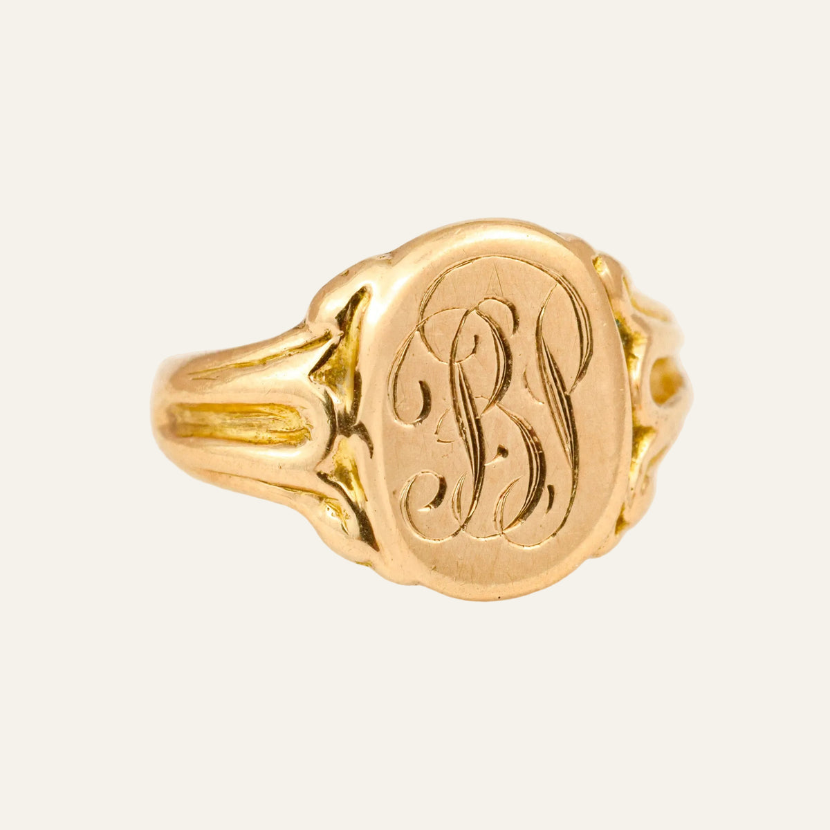 Antique 10k gold signet ring with a hand-engraved interlaced monogram on an oval face and fluted scroll shoulders.