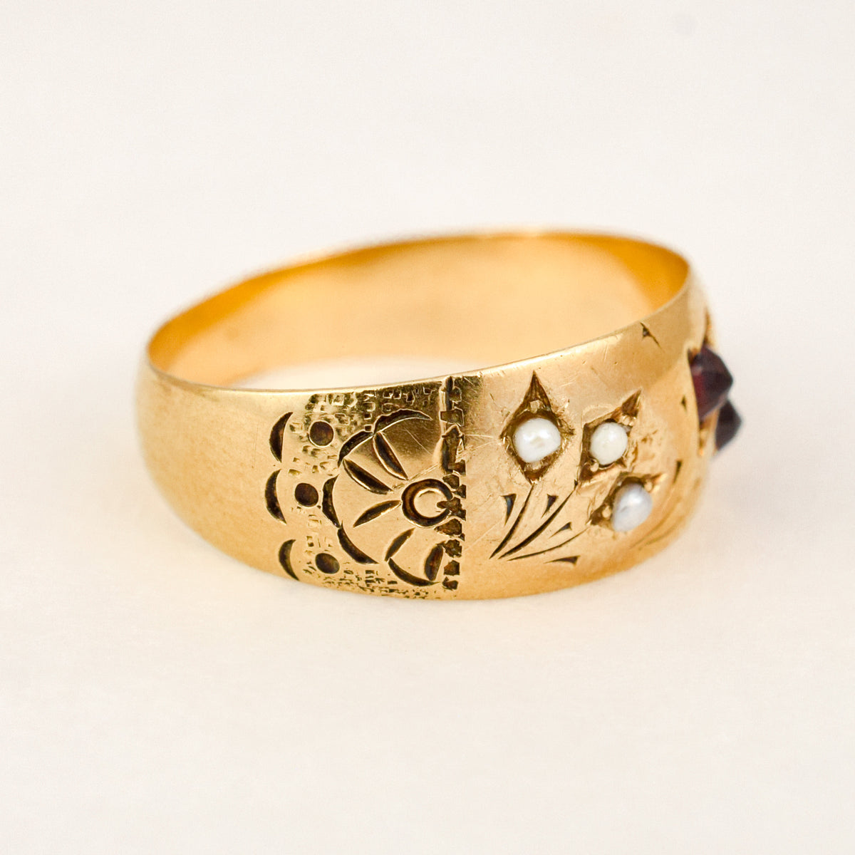 Shoulder detail of an antique 10k gold band, seed pearls star-set into engraved gold with a chased fan pattern.