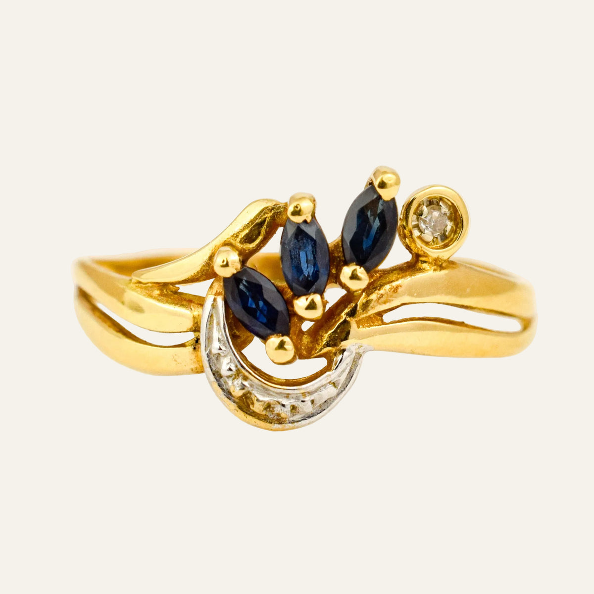 Vintage 14k gold ring with three marquise sapphires above a curve of pavé diamonds on a split band.