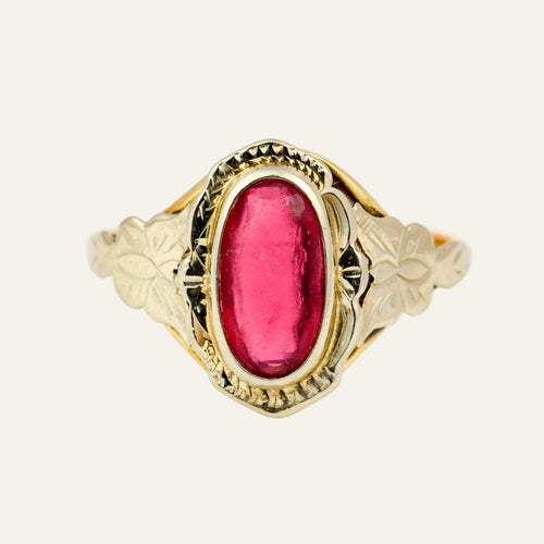 Retro 14k two-tone gold ring with an elongated pink-red topaz cabochon in a white gold bezel and carved leaf shoulders.