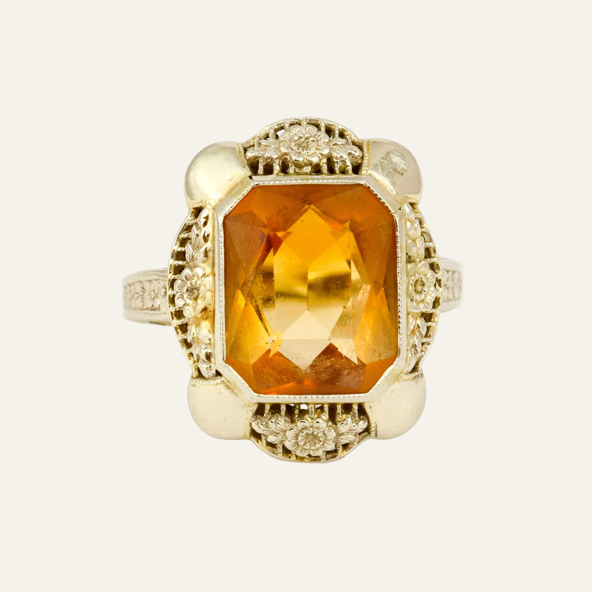 Art Deco 14k white gold ring with a large step-cut citrine framed by carved blossoms and small diamonds.