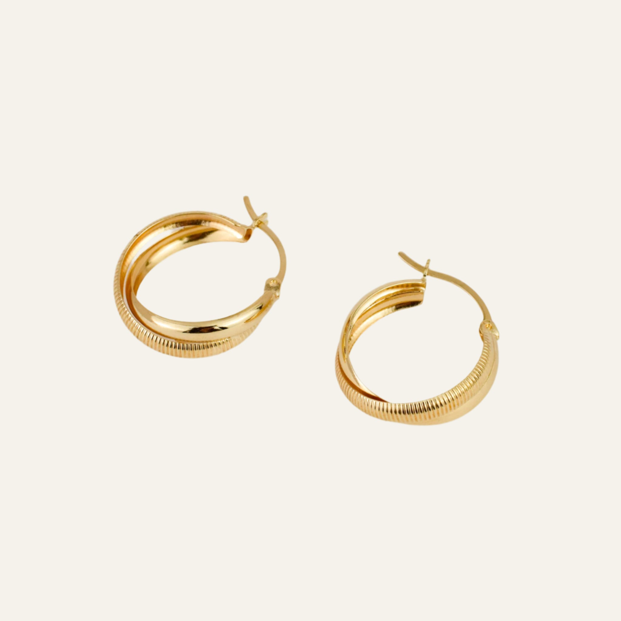 Gold hoop earrings on a light beige background