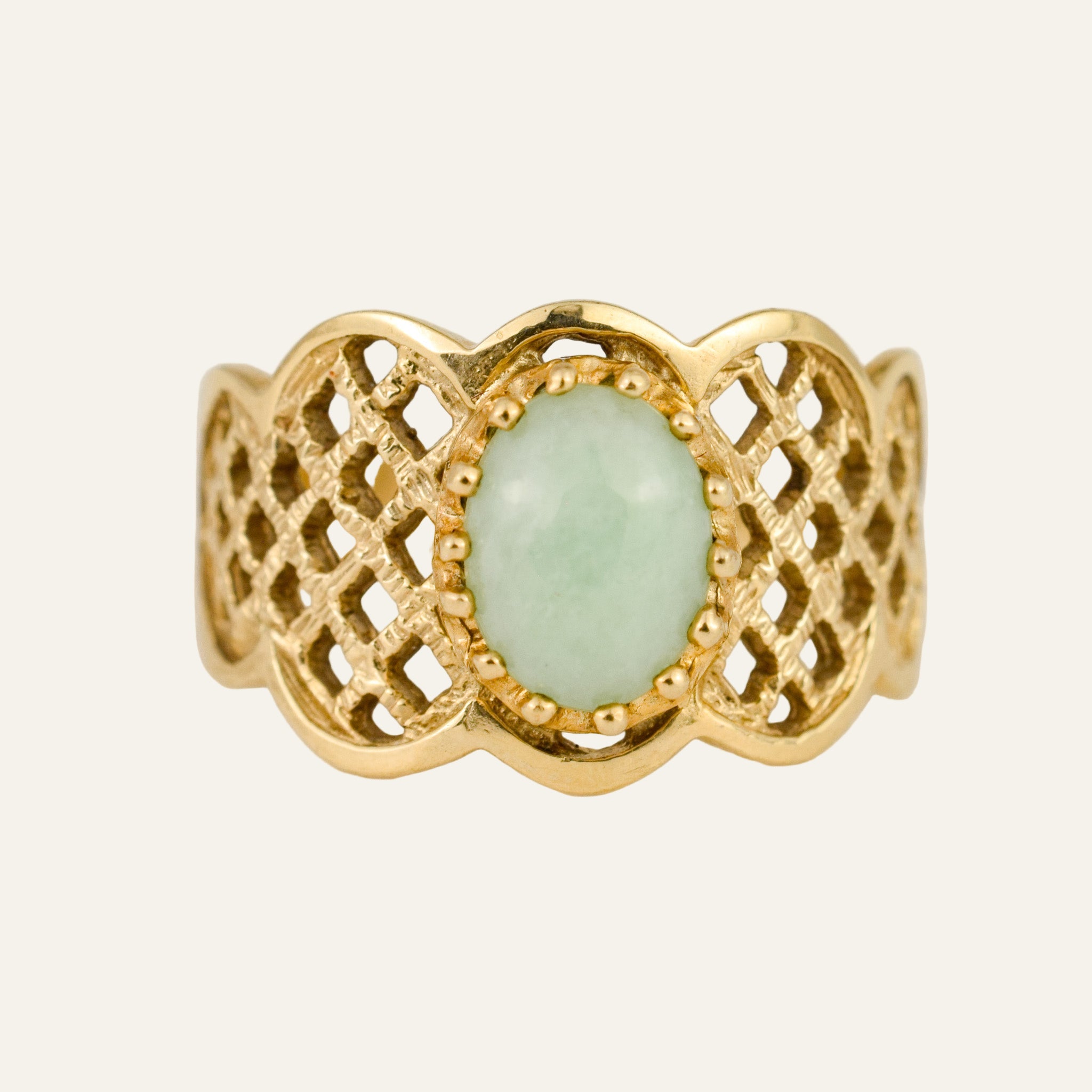Gold ring with a green gemstone on a light background