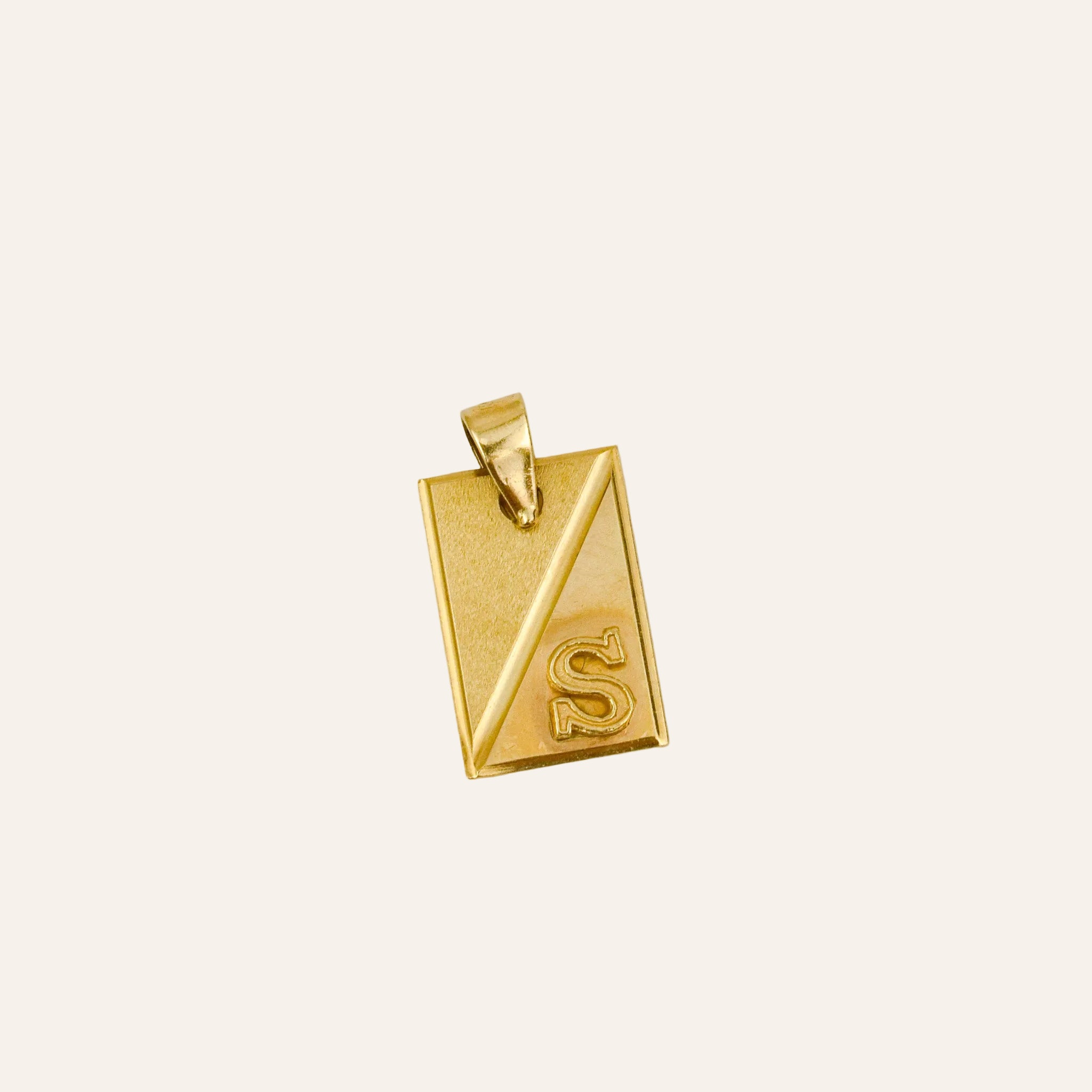 Gold pendant with 'S' on a light beige background