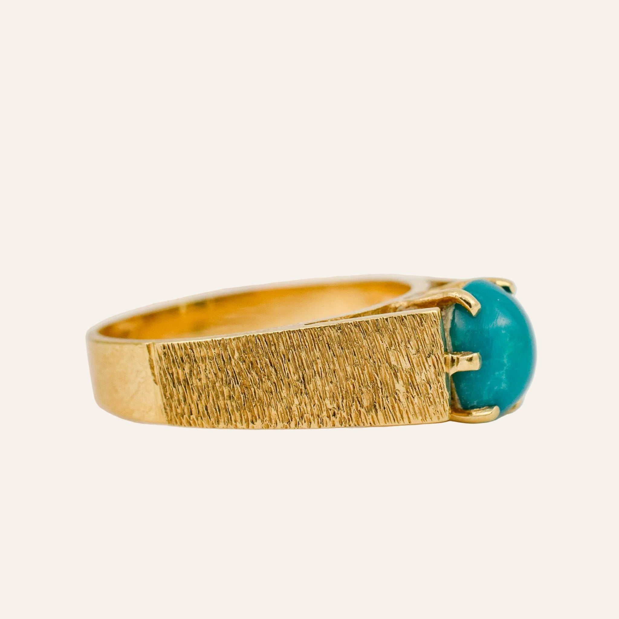 Gold ring with a turquoise stone on a light background