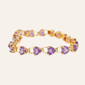 Gold bracelet with purple heart-shaped gemstones on a light beige background