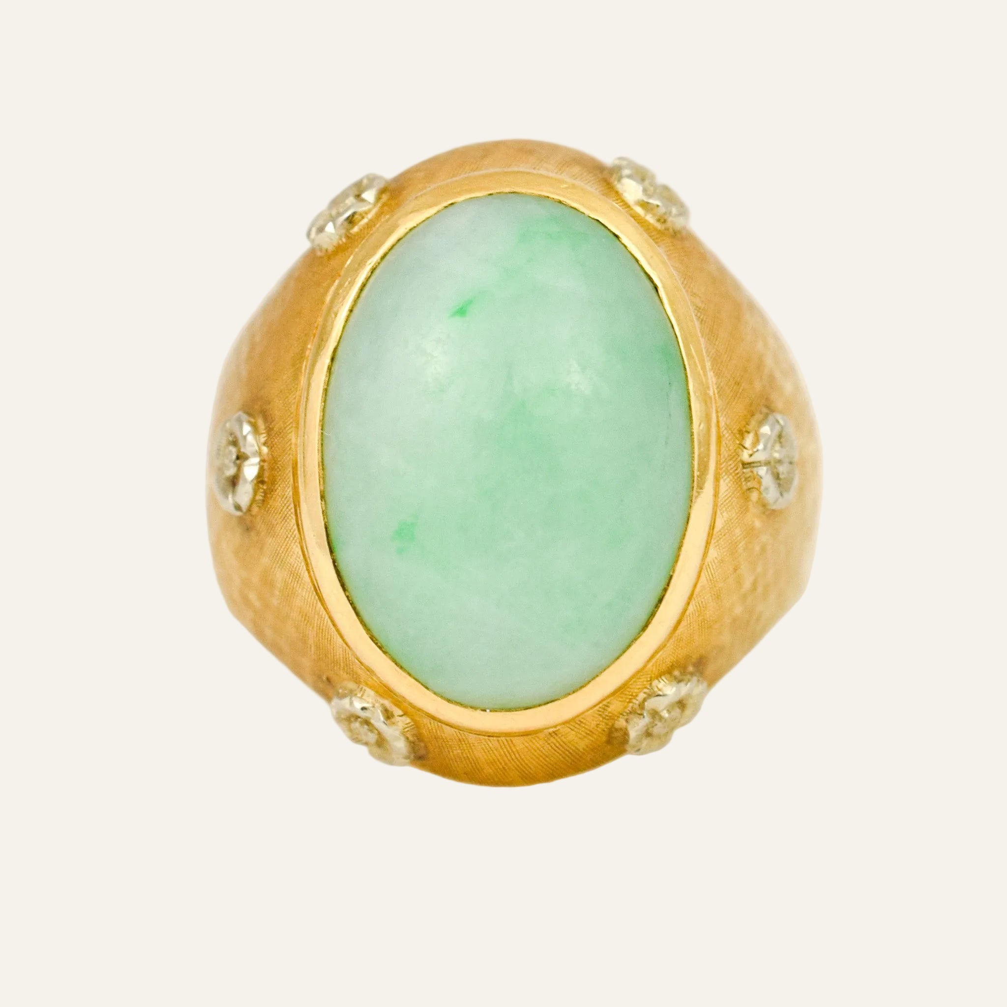 Domed 18k yellow gold ring with a large oval jade cabochon bezel-set at the centre and small diamonds in engraved floral stars around the textured band