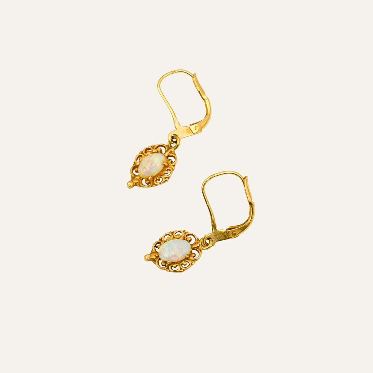 Vintage 14k gold leverback drop earrings with oval opals in pierced gold scrollwork frames.